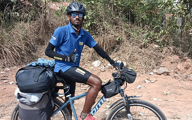 Young man rides a bicycle to teach environmental protection through travelling around the country